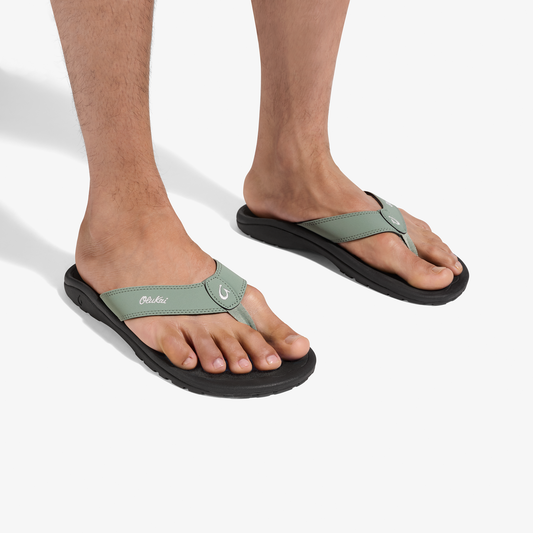 Man wearing seagreen and black thong sandals with black soles and adjustable straps.