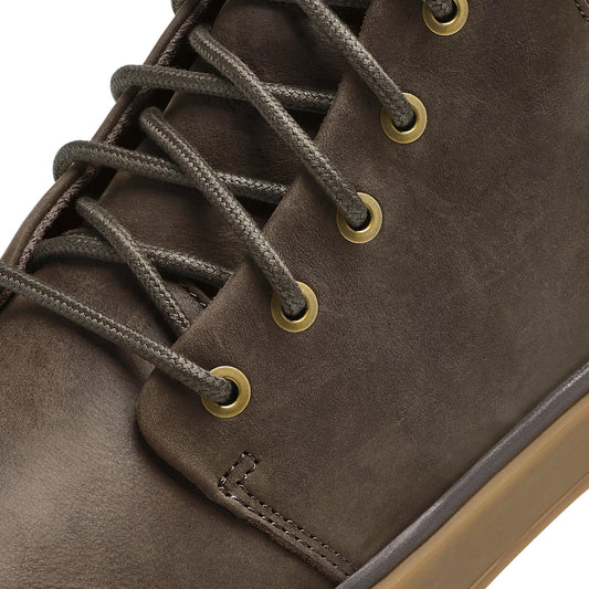 Dark brown suede boot with brass eyelets and gray laces, showing side detail and stitching.