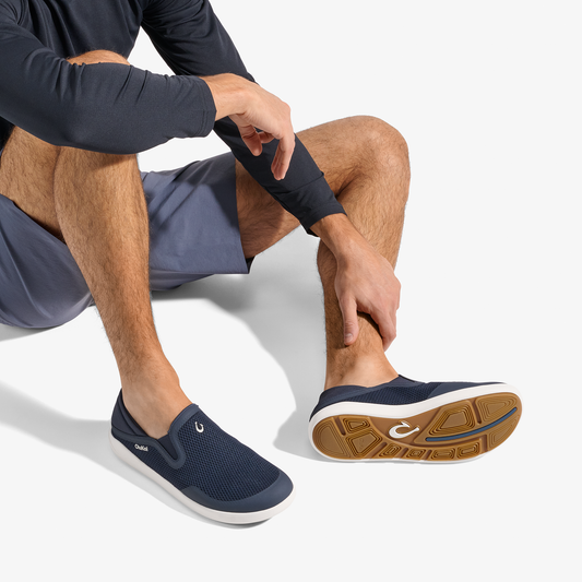 Navy slip-on shoe with white midsole and tan rubber sole, shown on foot with white background.