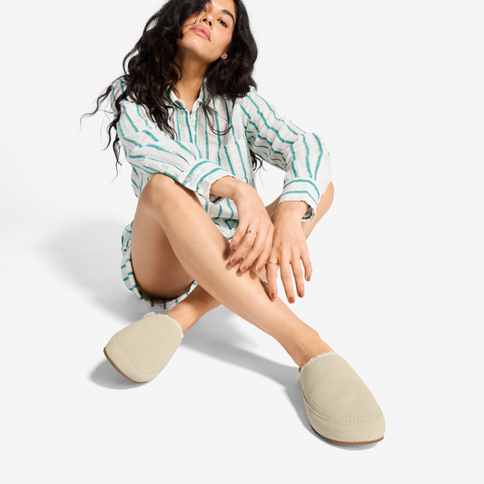 Woman wearing ecru and taupe striped button-up shirt with matching ecru suede slip-on loafers.