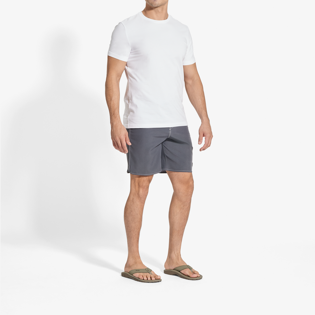 Man wearing white short-sleeve t-shirt, gray shorts, and gray sandals.