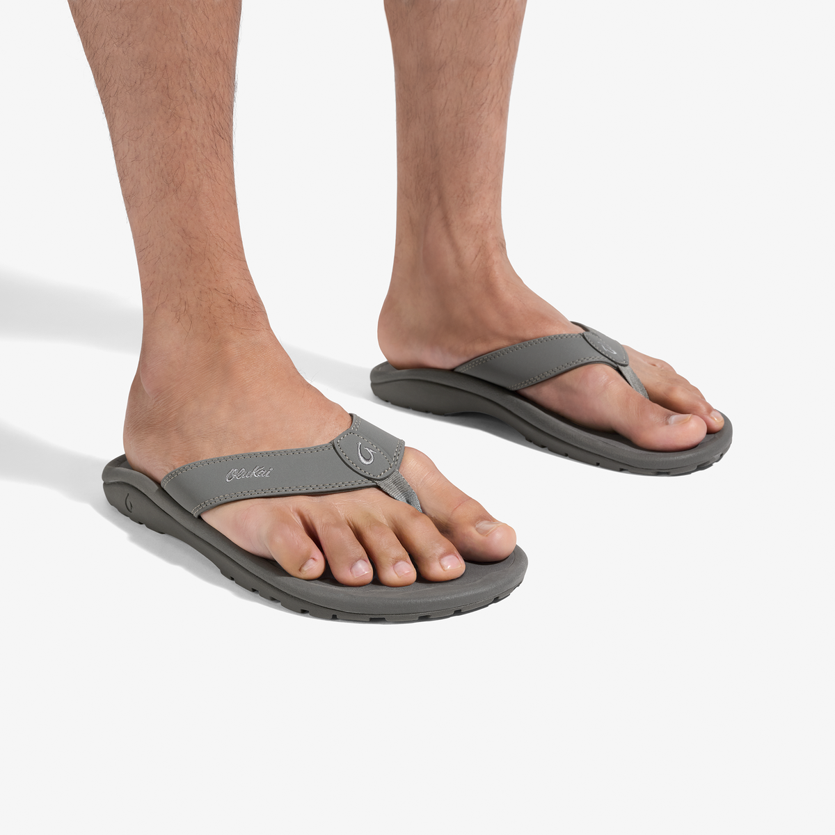 Gray thong sandals with curved footbeds and adjustable toe straps worn on bare feet.