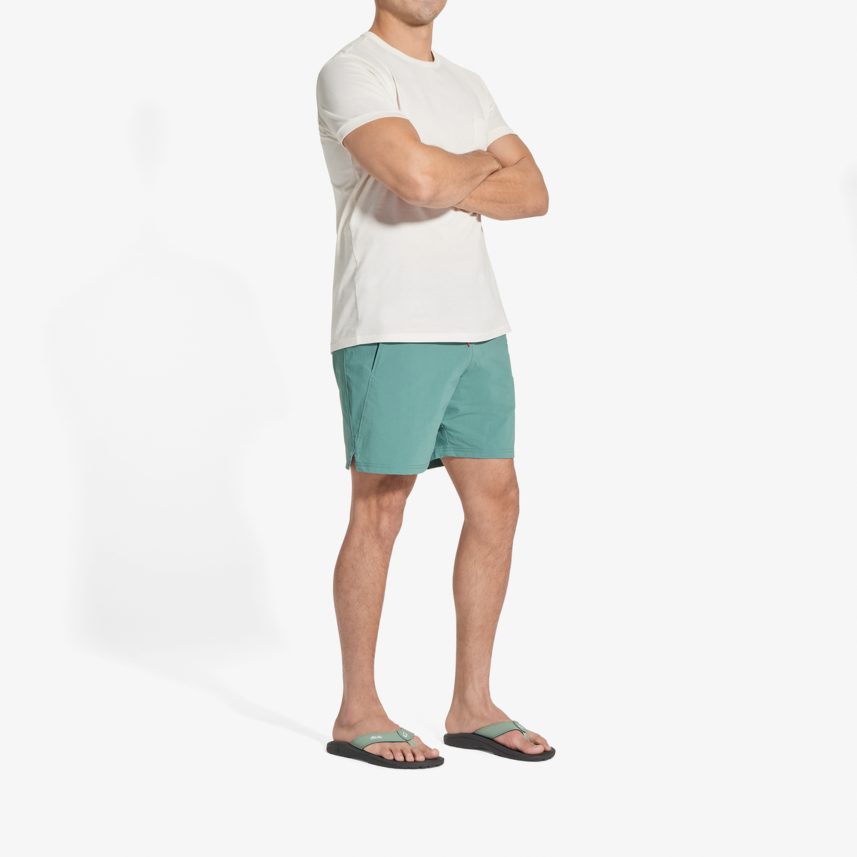 Man wearing cream short-sleeve shirt, seagreen shorts, and seagreen and black sandals.