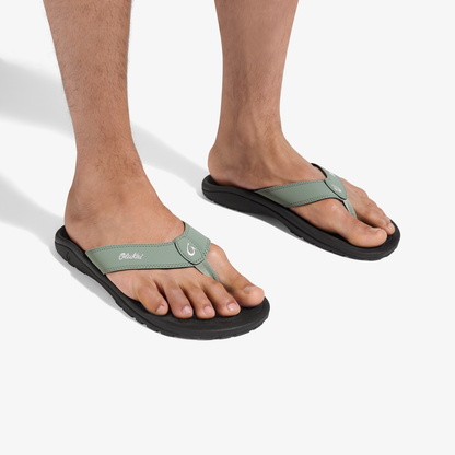 Man wearing seagreen and black thong sandals with black soles and adjustable straps.
