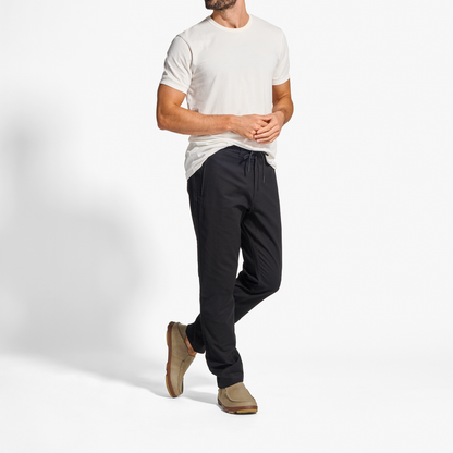 Man wearing cream short-sleeve t-shirt, black joggers, and tan suede slip-on shoes.
