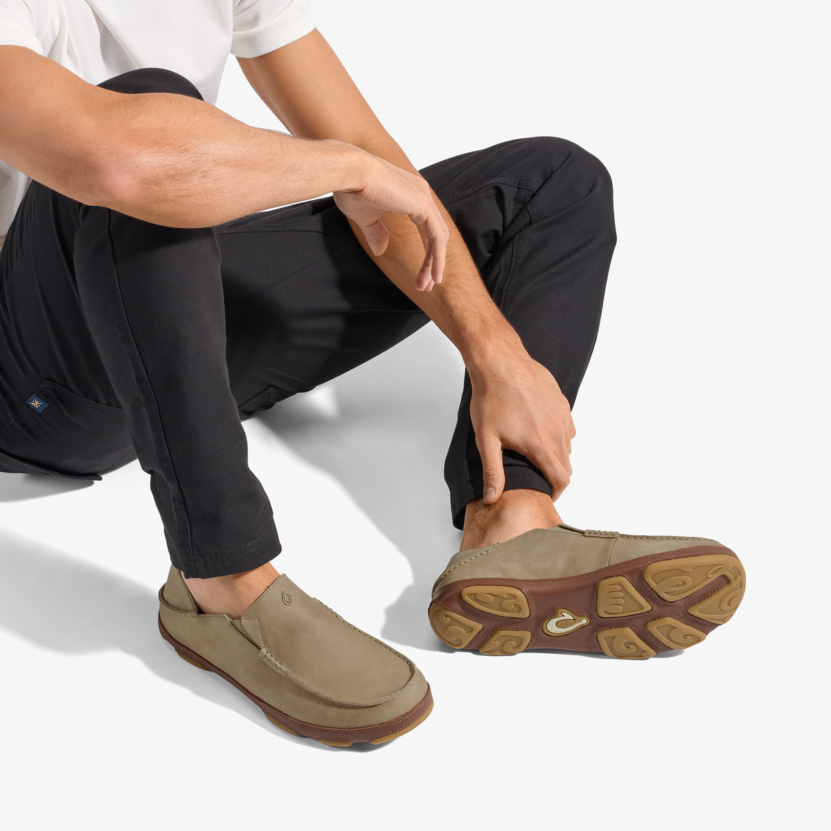 Person wearing clay-colored loafer-style shoe with brown sole, paired with black pants and white shirt.