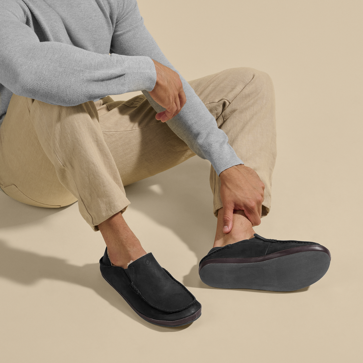 Black slip-on slipper with dark brown trim and cushioned sole, shown on foot.