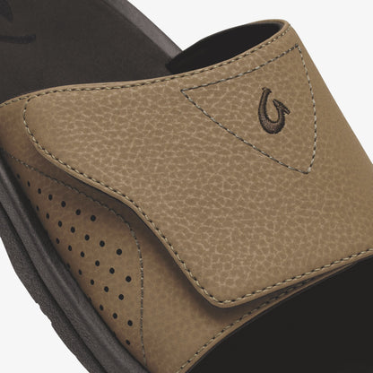 Tan leather slide with dark sole, featuring a horseshoe logo and perforated side panel detail.