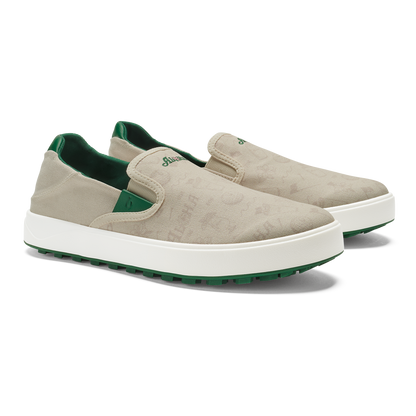 Beige canvas slip-on sneakers with white sole, green heel lining and green rubber outsole.