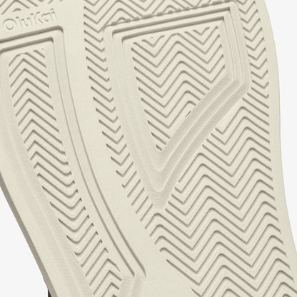Cream-colored shoe sole with geometric chevron tread pattern and brand marking.