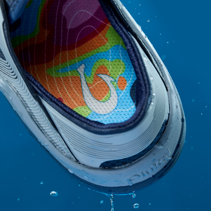 Shoe sole displaying colorful rainbow gradient pattern with white swoosh symbol on blue background.