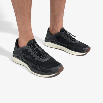 Black lace-up running shoes with cream soles and brown heel accents, worn on feet.