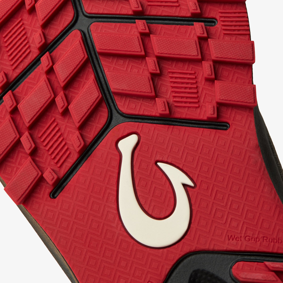 Red rubber sole with textured tread pattern, black trim, and white curved hook logo detail.