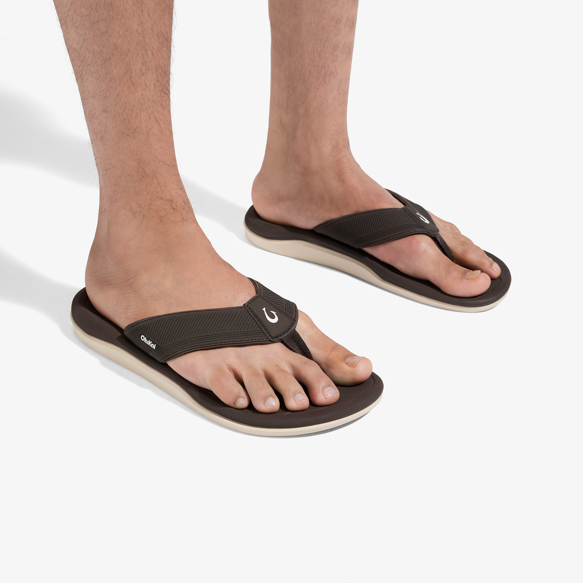 Dark java thong sandals with black straps and cream-colored soles worn on bare feet.
