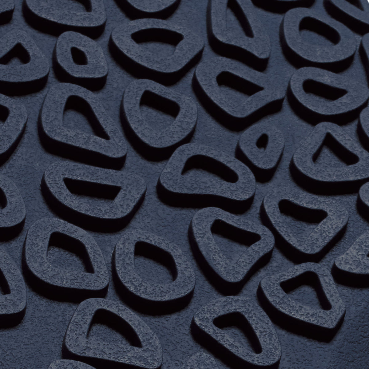 Close-up of textured fabric surface in deep blue with raised geometric pattern and shadowed details.