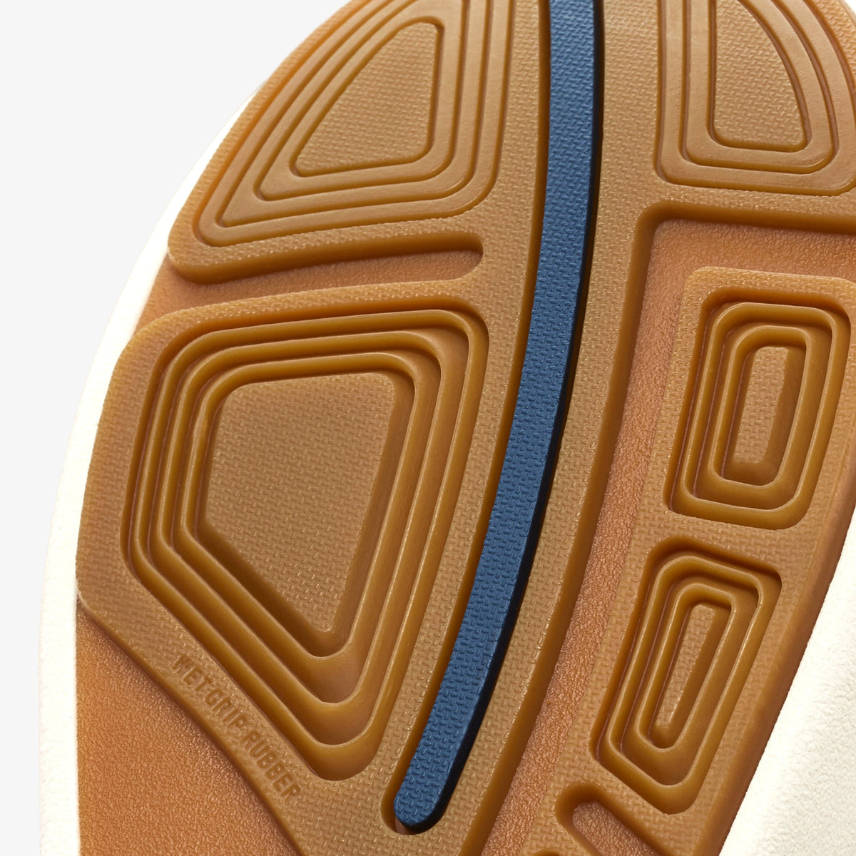Tan rubber sole with rounded geometric pattern and blue stripe detail down the center.