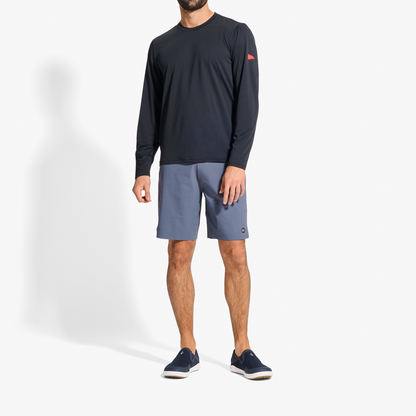 Man wearing dark navy long-sleeve shirt, blue shorts, and dark slip-on sneakers.