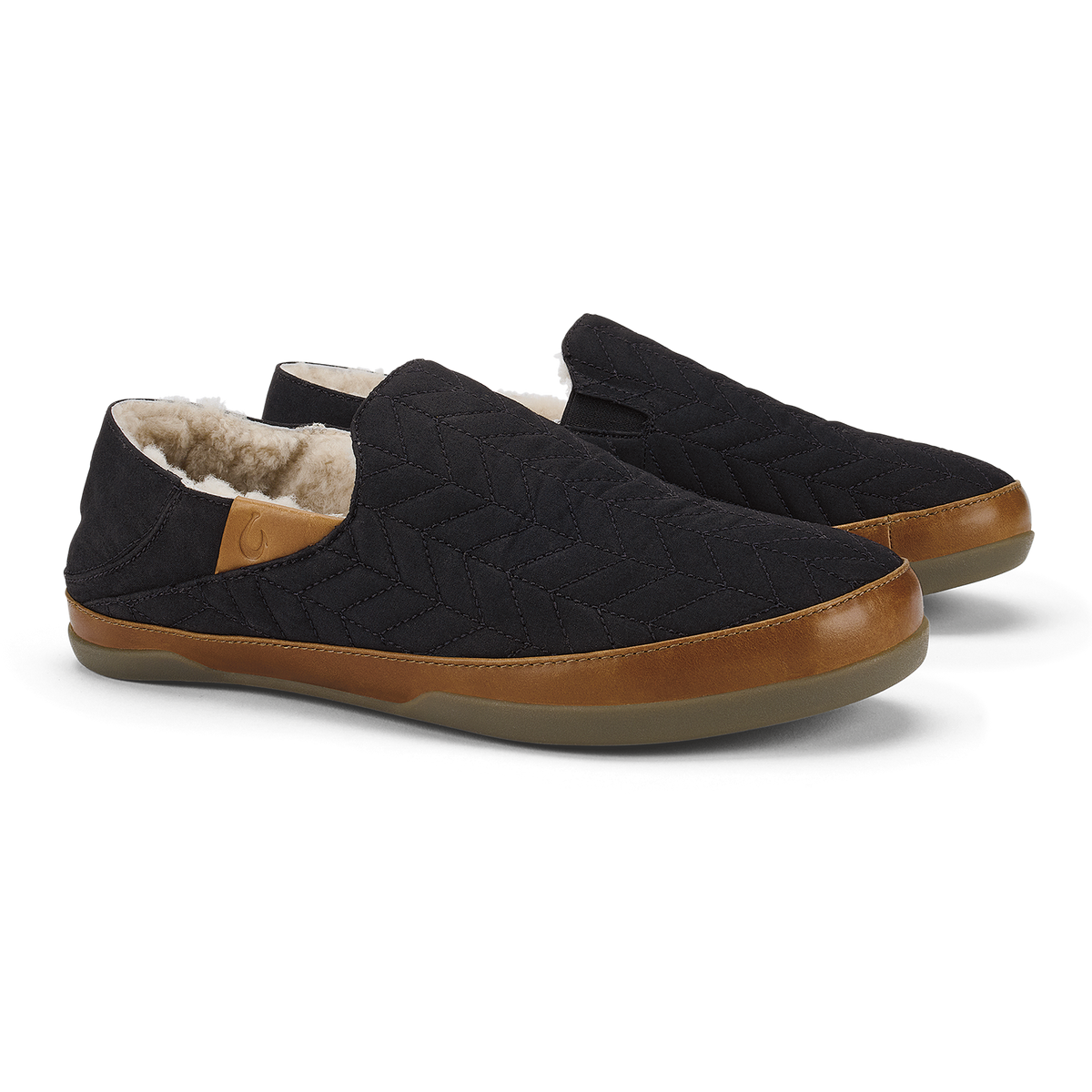 Black quilted slip-on slippers with tan leather trim and fleece lining.