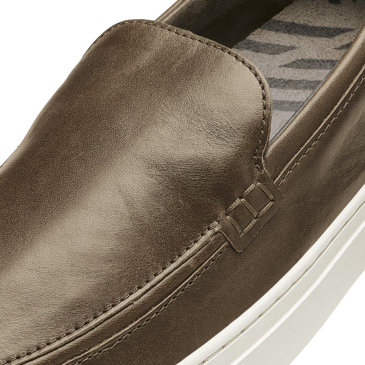 Walnut leather slip-on shoe with white sole and geometric patterned insole detail.
