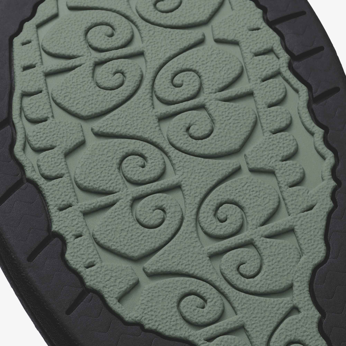 Sage green sole with embossed spiral and leaf pattern, black heel trim visible.