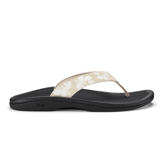 Black flip-flop sandal with beige thong strap featuring white floral pattern and dotted design.