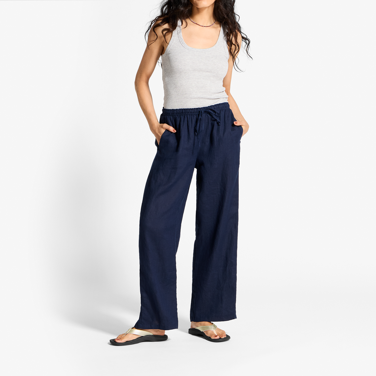 Woman wearing light gray sleeveless tank top and navy wide-leg pants with drawstring waist and side pockets.