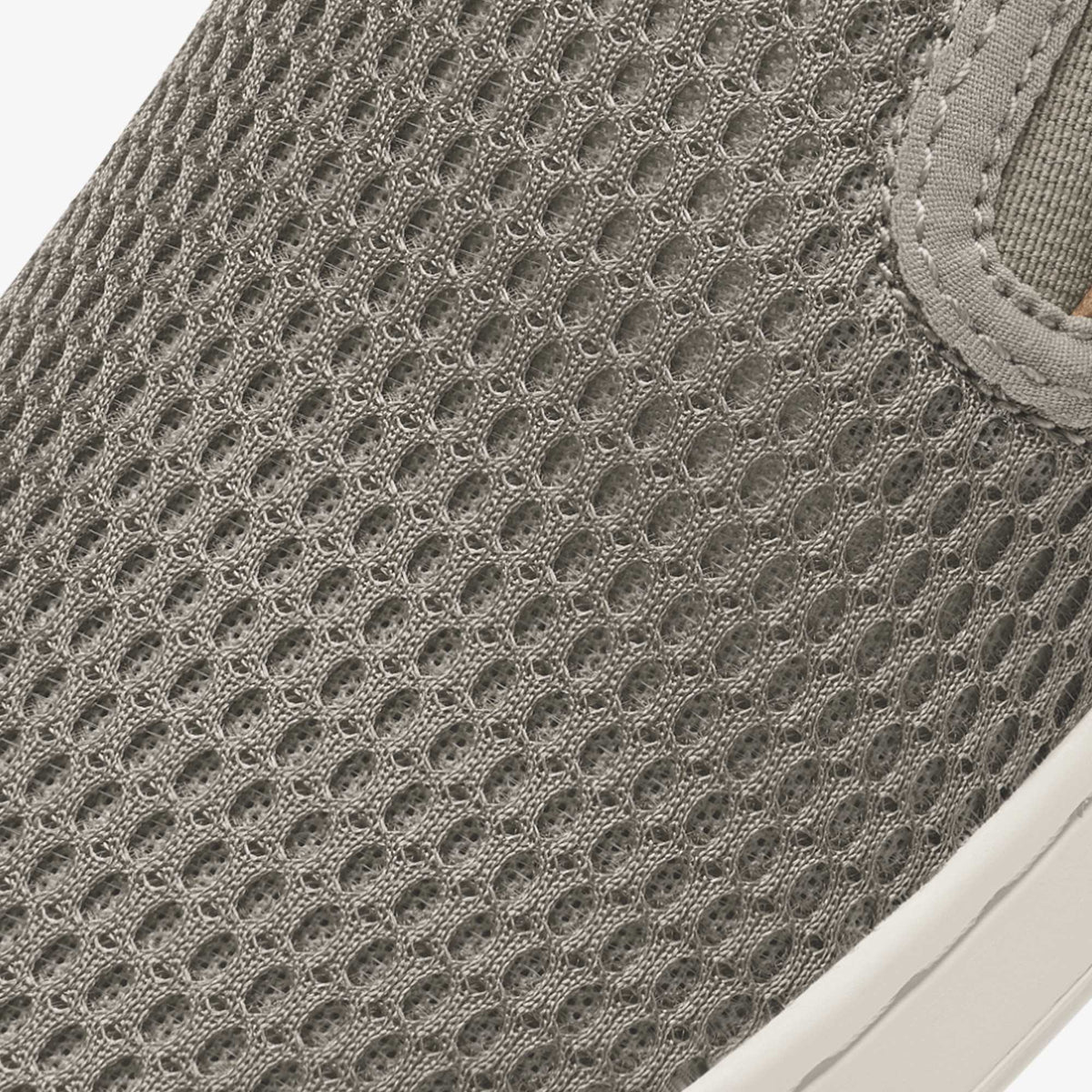 Taupe grey slip-on shoe with textured knit mesh upper and white sole.
