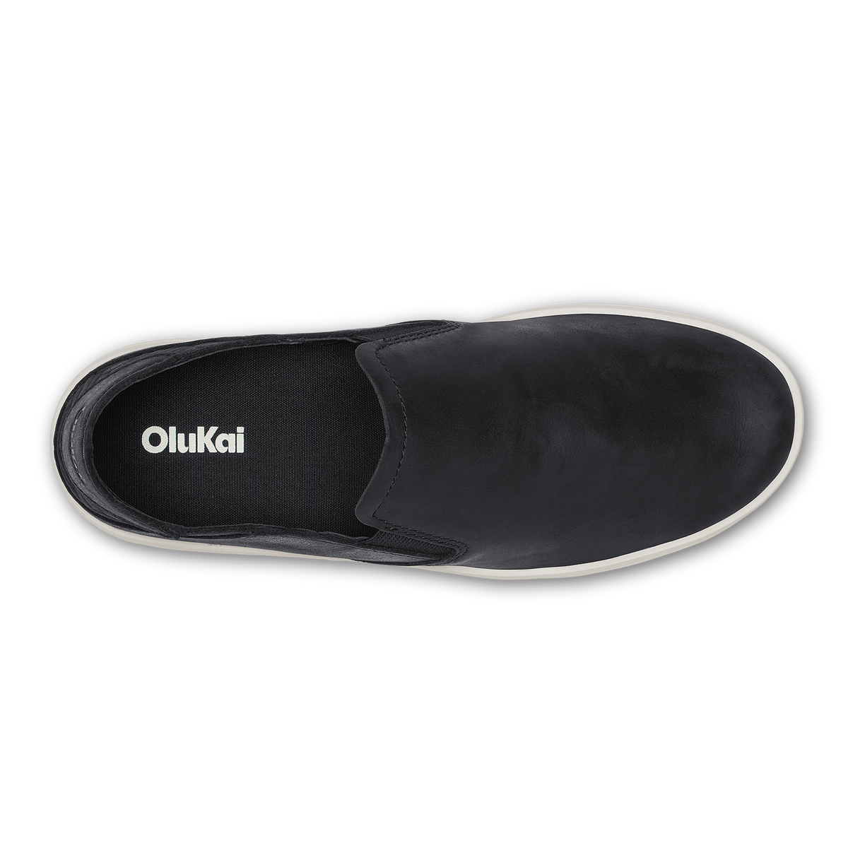 Black leather slip-on shoe with white sole and OluKai branding on insole, viewed from above.