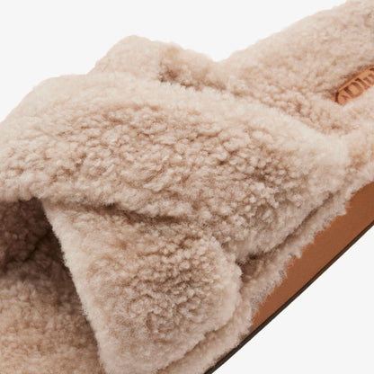 Tan fleece slipper with soft textured upper and brown sole detail visible.