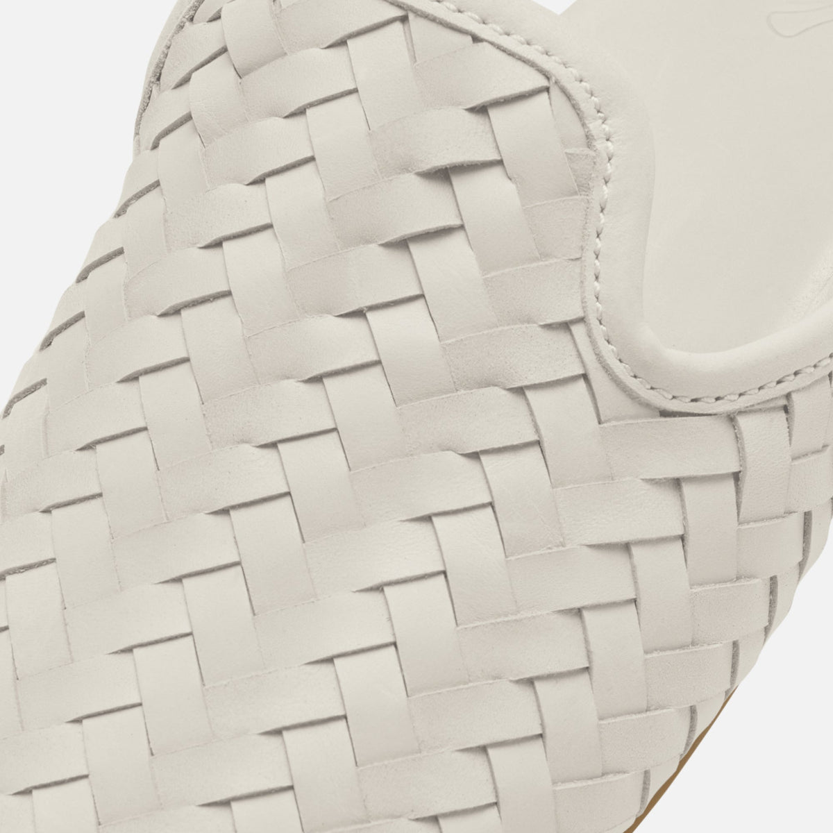 Cream-colored woven leather bag with interlocking basket weave pattern and curved handle detail.