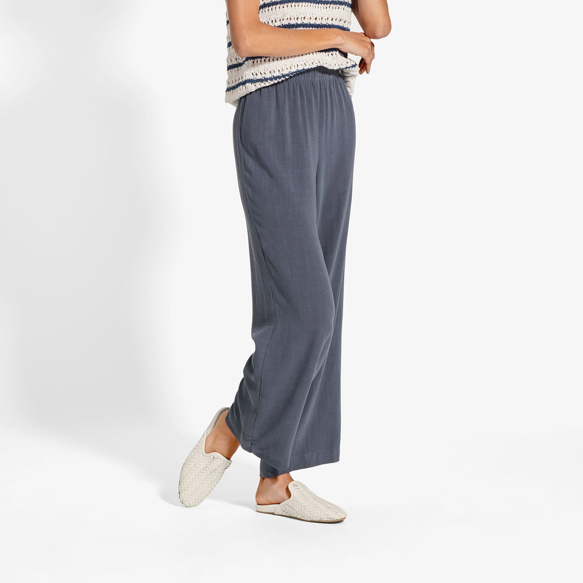 Gray wide-leg pants with elastic waistband paired with white woven slip-on shoes.