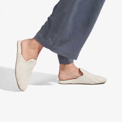 Cream woven flat mules with backless design, worn with charcoal joggers.