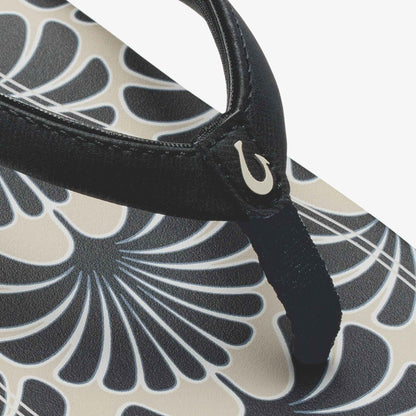 Black leather shoulder bag with cream and gray geometric shell pattern and curved handle detail.