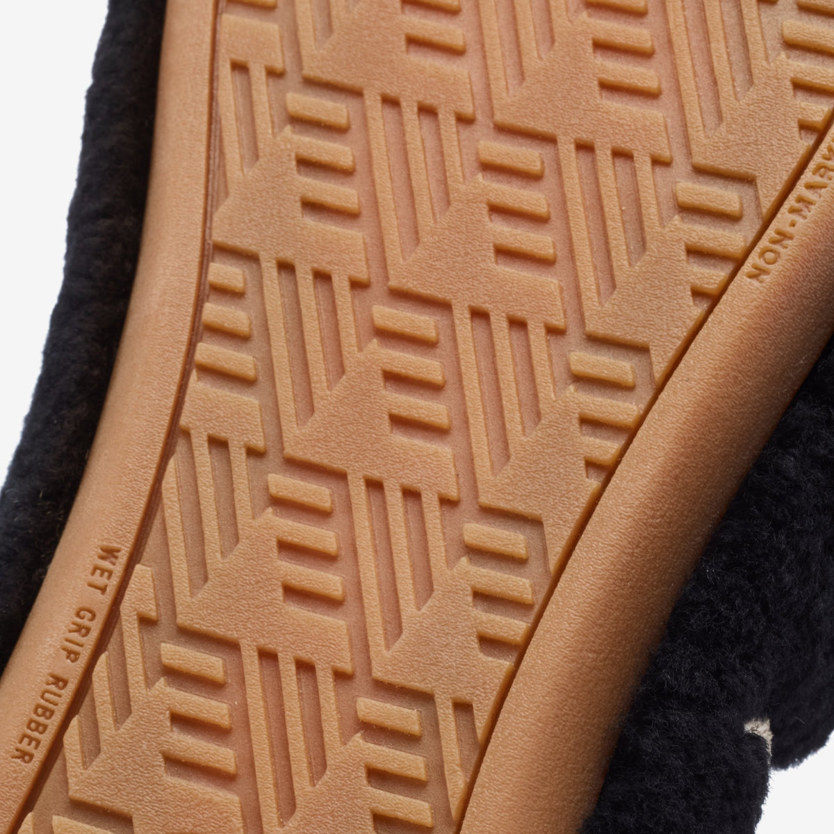 Black mule with tan rubber sole featuring geometric tread pattern.