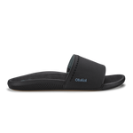 Black slide sandal with padded upper and textured sole featuring OluKai branding.