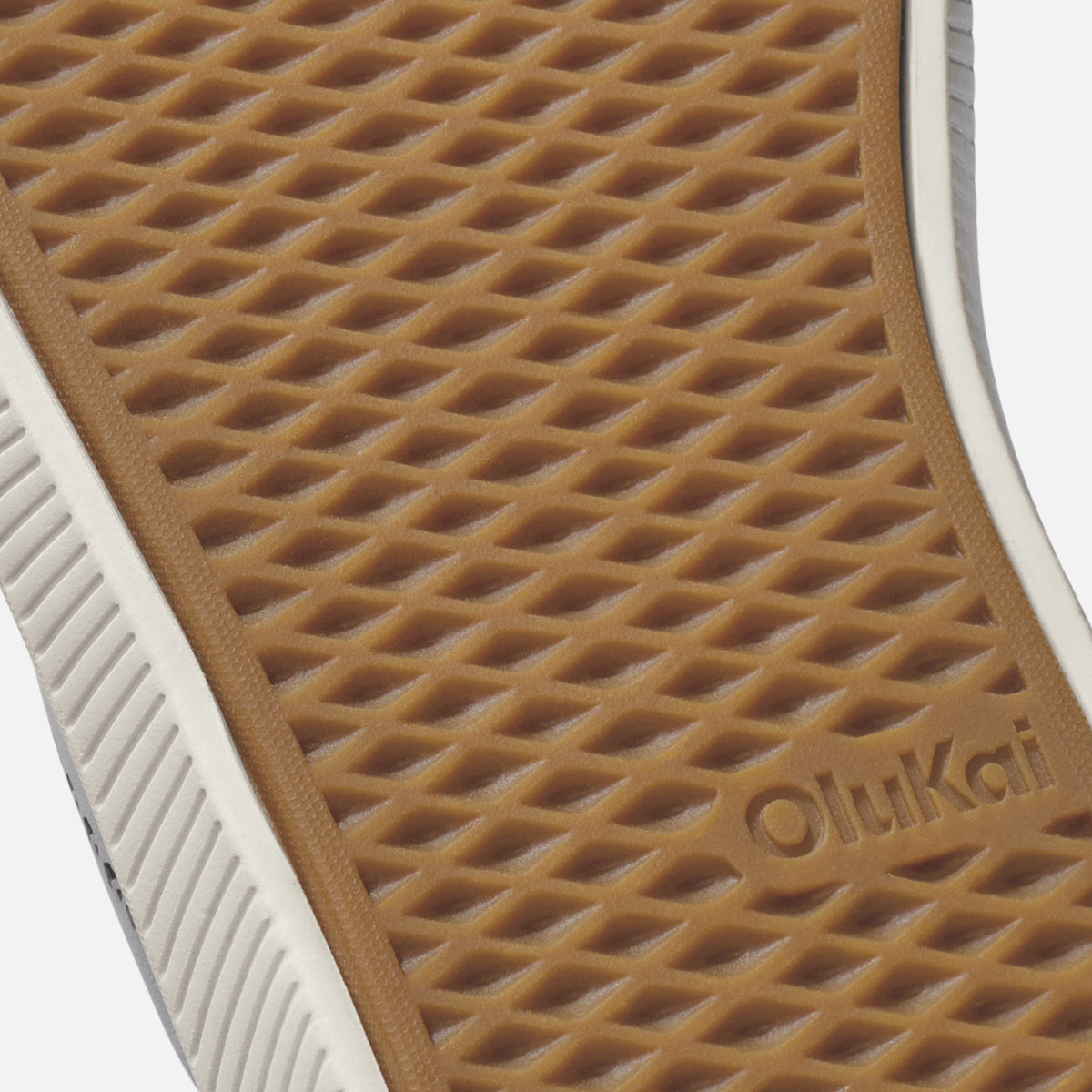 Tan rubber sole with diamond tread pattern and "olukai" branding, white midsole stripe visible on edge.