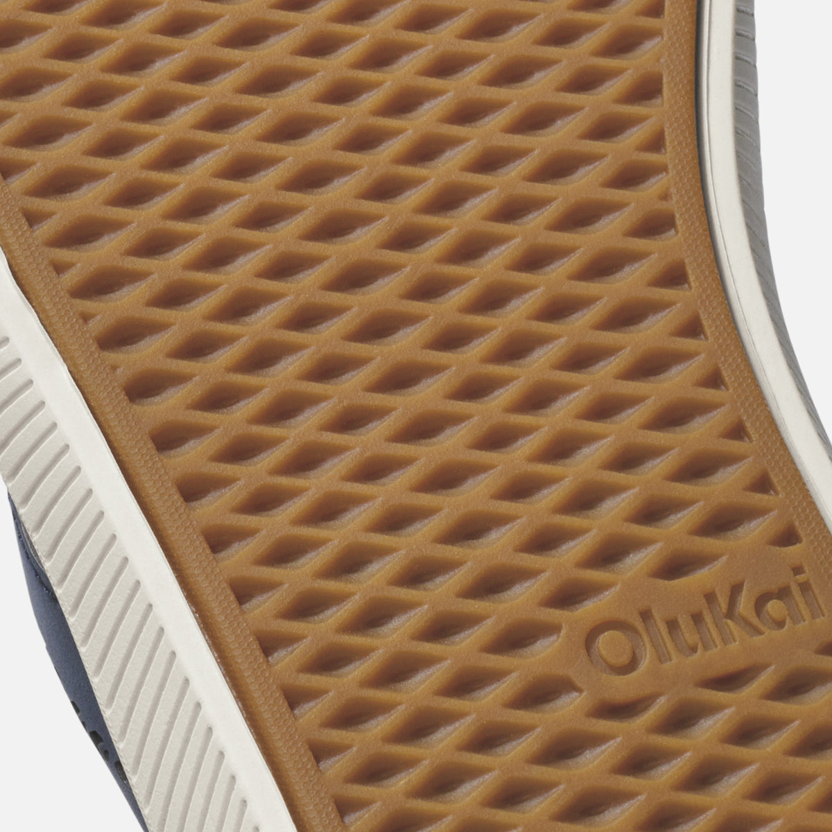 Tan waffle-textured sole with white and navy stripe, showing OluKai branding.