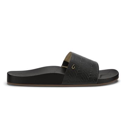 Black slide sandal with woven texture upper, tan footbed, and metallic accent buckle.