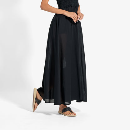 Black maxi skirt with smocked waistband worn with black and tan slide sandals.