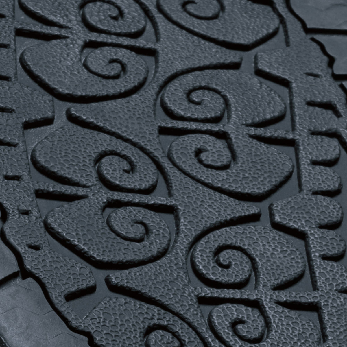 Dark textured surface with embossed spiral and geometric patterns in relief.